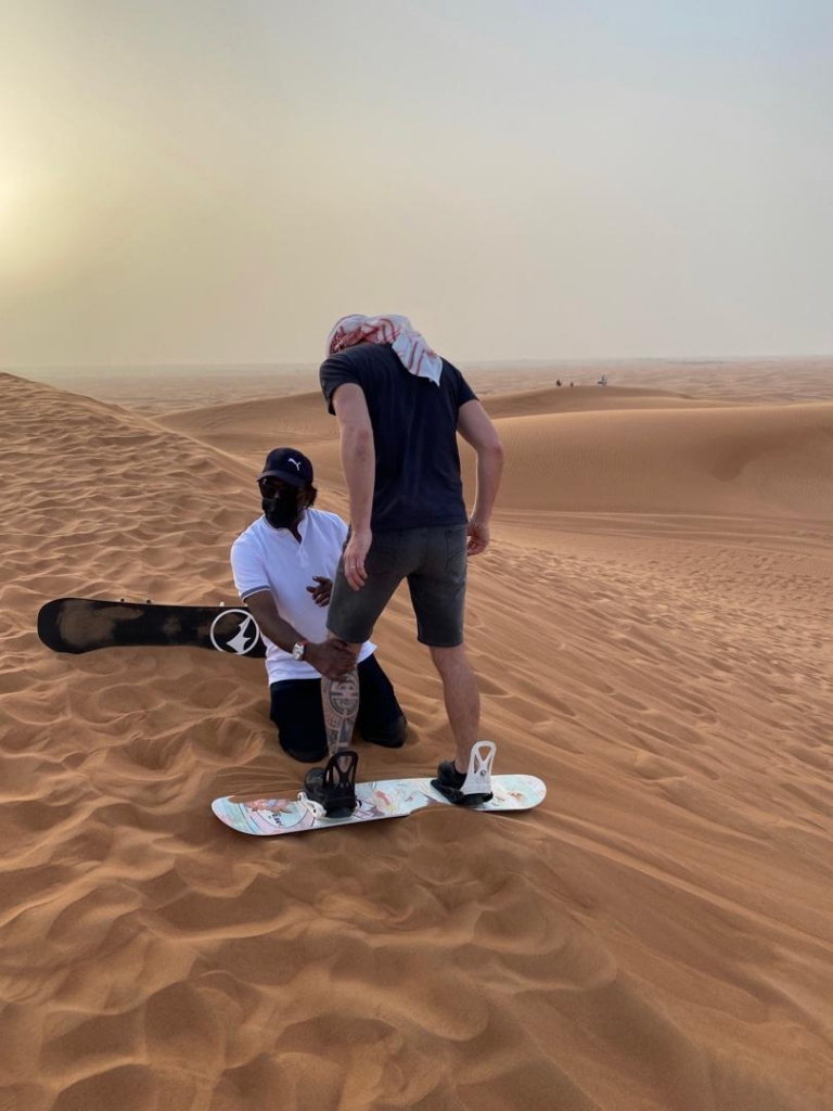 Sandboarding and dune surfing in the Dubai desert during a 4x4 safari excursion